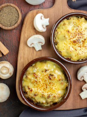 top-view-tasty-julienne-bowls-chopping-board-wooden-spoons-spices-small-bowls-mushrooms-brown